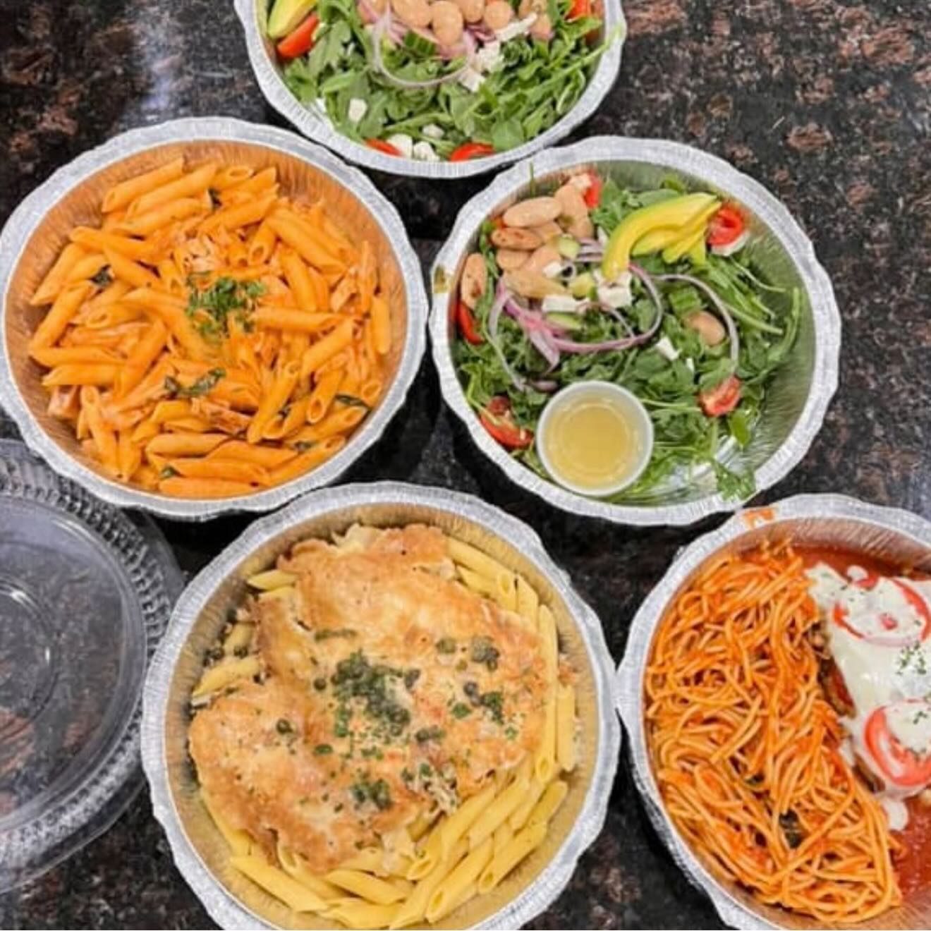 Takeout pans of penne, chicken, salad and spaghetti ready for pickup