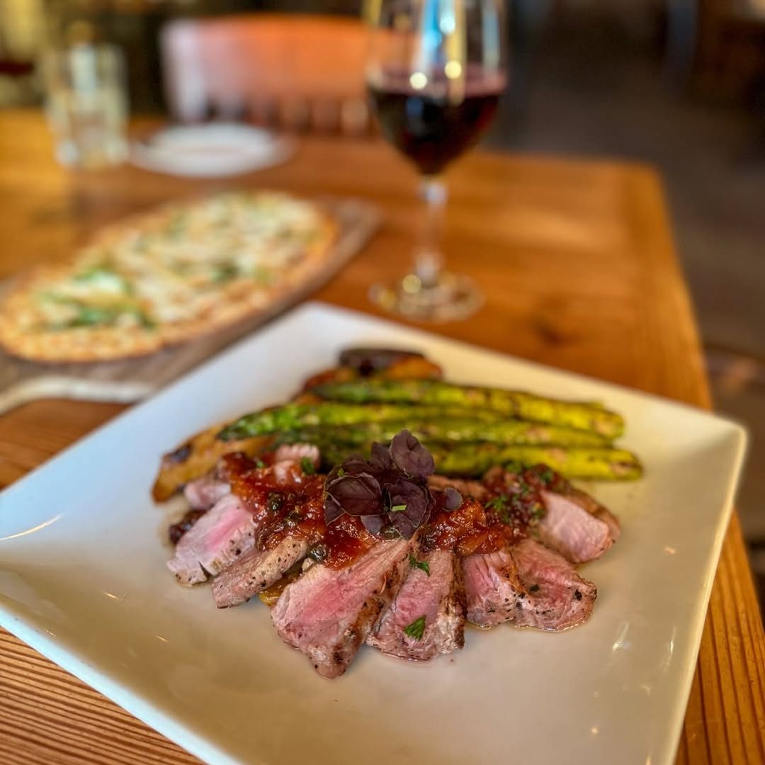 Sliced steak with grilled asparagus and a glass of red wine